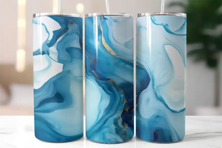 Three Blue And Gold Marble-Patterned Tumblers With Straws.