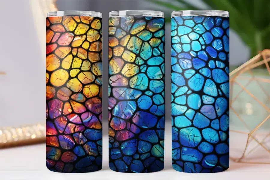 Three tumblers with a stained-glass style design.  The designs feature multicolored, irregular shapes separated by black lines.  One tumbler is predominantly warm colors, one cool colors, and the other a mix of both.