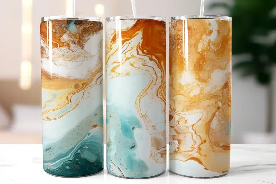Three Tall Tumblers With Abstract Marble Designs In Teal, Blue, And Gold.