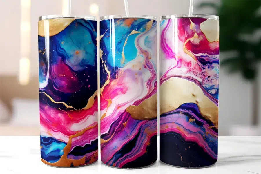 Three Tall Tumblers With Vibrant Pink, Blue, Purple, And Gold Marble Designs.