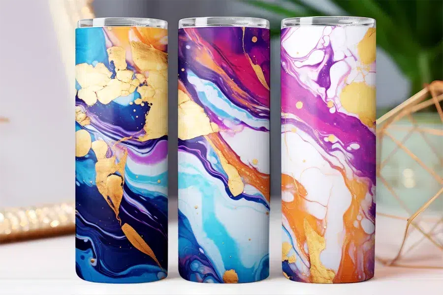 Three tumblers with abstract marble designs in purple, blue, and orange with gold accents.