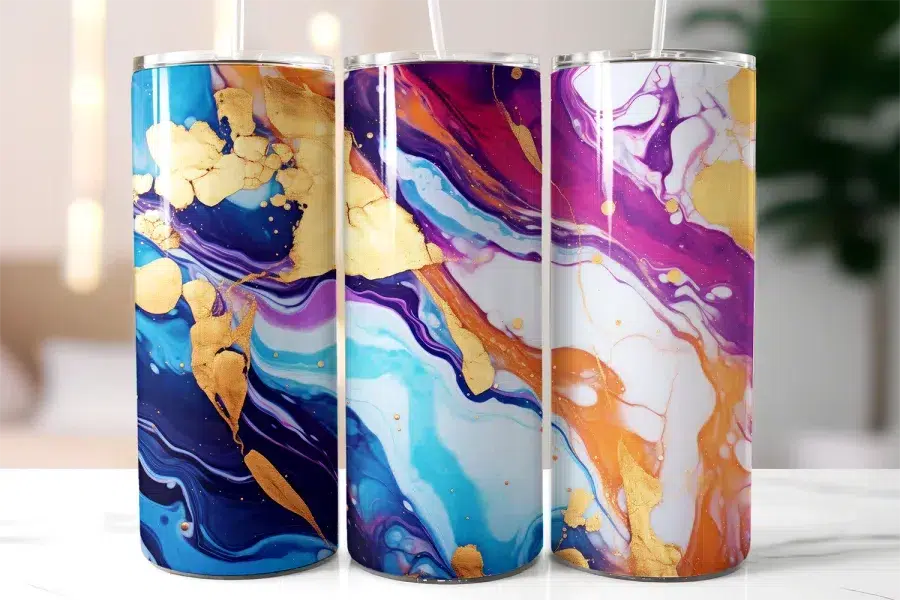 Three Stainless Steel Tumblers With Abstract Marble Designs In Shades Of Purple, Blue, Orange, And Gold.