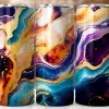 Three Stainless Steel Tumblers With Abstract Marble Designs In Shades Of Blue, Purple, Gold, And Orange.