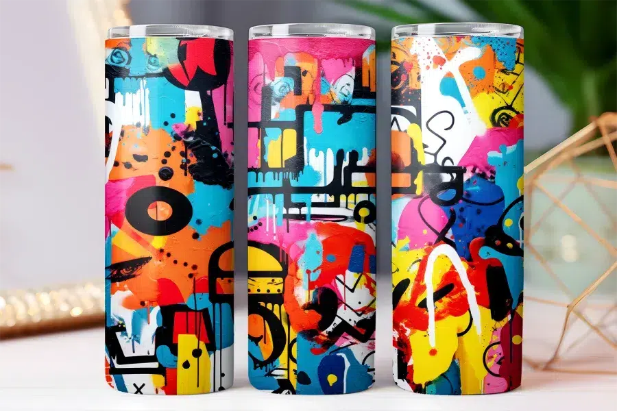 Three colorful tumblers with abstract graffiti designs.