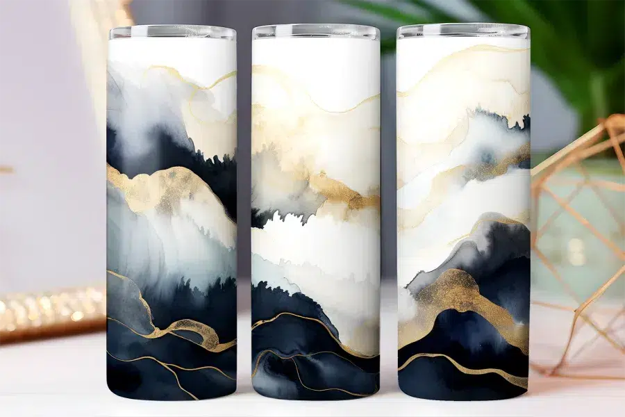 Three tumblers with an abstract design of navy, gray, and gold watercolor-style waves.