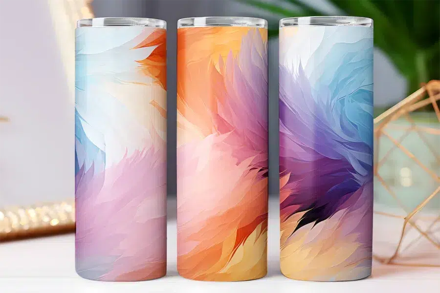Three pastel-colored tumblers with an abstract feather design.