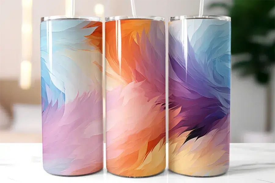 Three Stainless Steel Tumblers With Abstract Feather Designs In Pastel Colors.