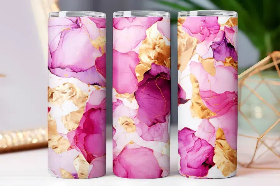 Three tall tumblers with pink and gold abstract designs.