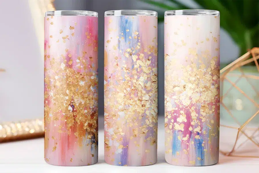 Three tall tumblers with an abstract design featuring pink, gold, and blue splatter paint.