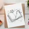Line Drawing Of An Open Book With A Fountain Pen Resting On The Pages, Surrounded By Small Flowers And Stars.