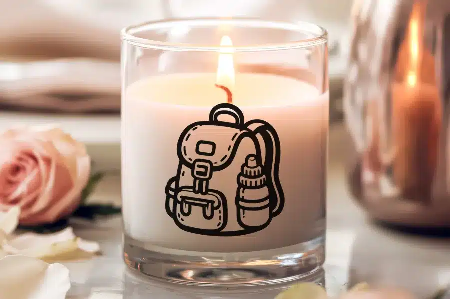 A Lit Candle In A Glass Jar With A Backpack And Water Bottle Design.
