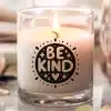 A Lit Candle In A Glass Jar With The Words Be Kind In A Decorative Circle.