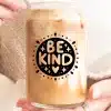 A Person'S Hands Holding A Glass Iced Coffee Can With The Words Be Kind In A Circular Design.