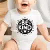 Baby Wearing A White Onesie With A Black Circle Design That Says Be Kind.