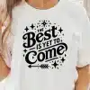 Woman Wearing A White T-Shirt With A Black Design That Says The Best Is Yet To Come.