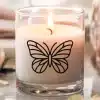 A Lit Candle In A Glass Jar Decorated With A Black Butterfly Design.
