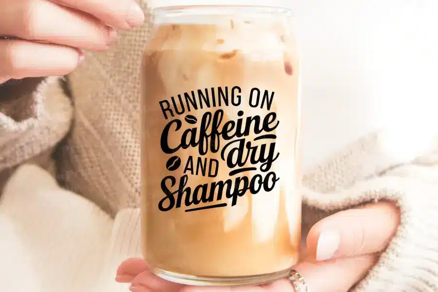 Hands Holding A Glass Iced Coffee With The Text Running On Caffeine And Dry Shampoo.
