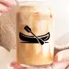 Hands Holding A Glass Jar Filled With Iced Coffee, Featuring A Canoe And Paddle Graphic.