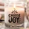 A Lit Candle In A Clear Glass Jar With The Words Choose Joy In Black Lettering.
