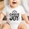 Smiling Baby Wearing A White Onesie That Says Choose Joy.