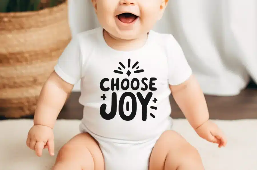 Smiling Baby Wearing A White Onesie That Says Choose Joy.