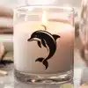 A Lit Candle In A Glass Jar Features A Black Dolphin Design.