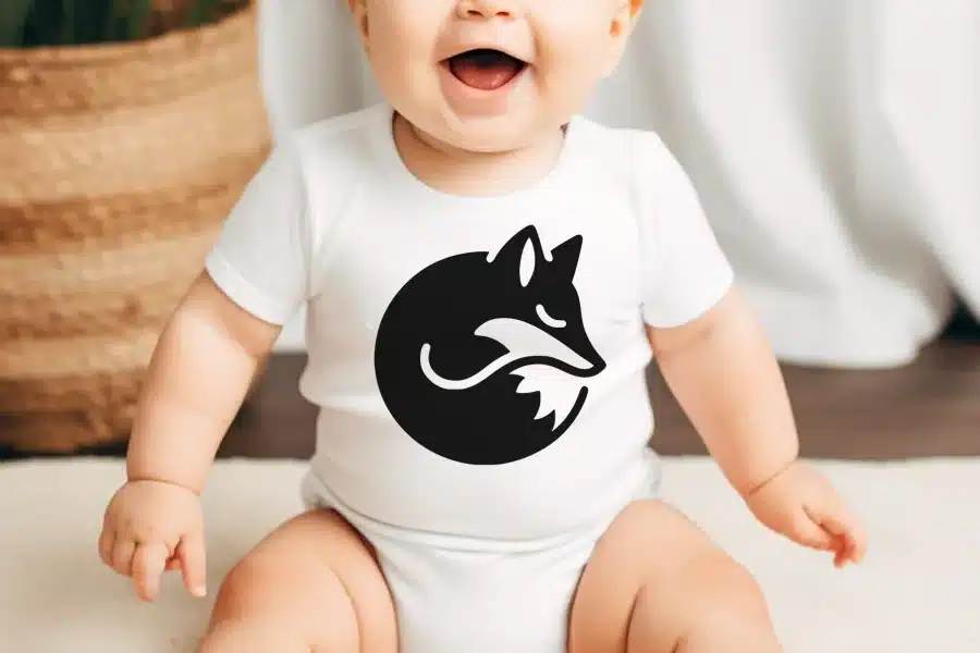 Baby wearing a white bodysuit with a black fox design.
