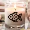 A Lit Candle In A Glass Jar With A Black Fish Illustration On The Side.