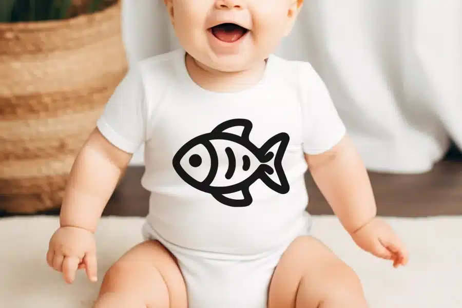 Baby wearing a white onesie with a black fish graphic.
