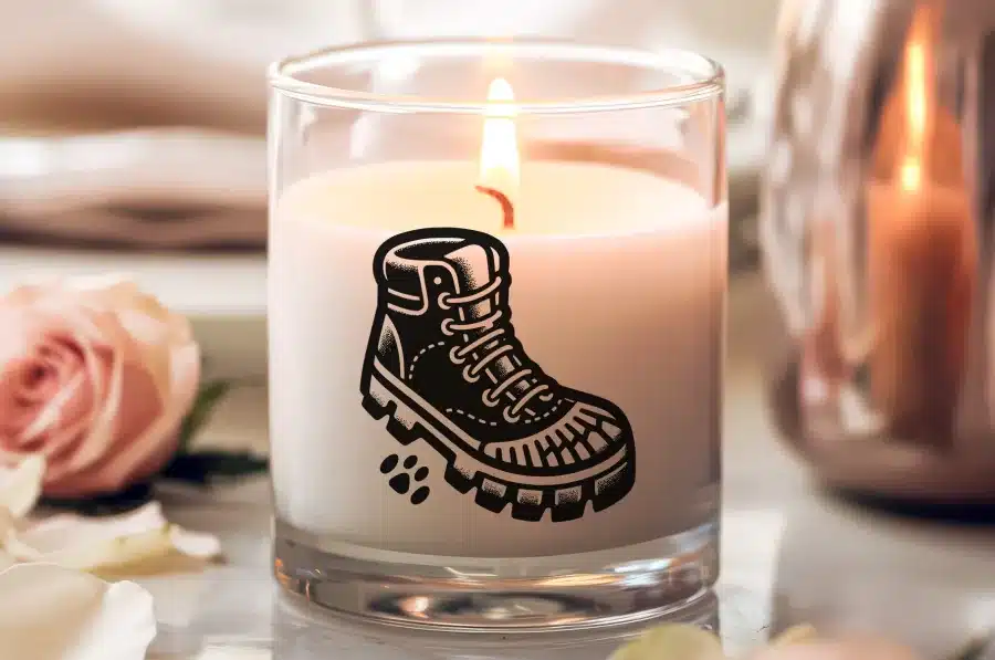 A Lit Candle With A Black Boot Graphic On Its Side.