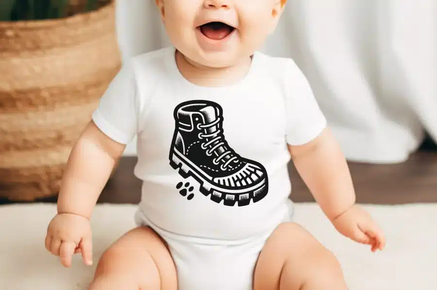 Baby Wearing A White Onesie With A Black And White Illustration Of A Hiking Boot.