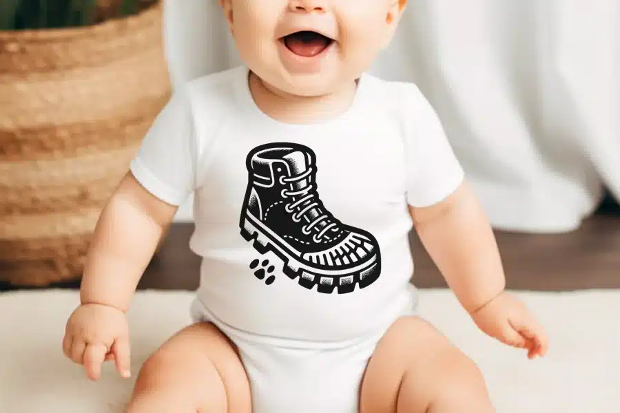 Baby wearing a white onesie with a black and white illustration of a hiking boot.