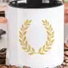 White Coffee Mug With Black Handle, Featuring A Gold Laurel Wreath Design.