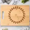 Light Brown Bamboo Cutting Board With A Dark Brown Engraved Wreath Design.