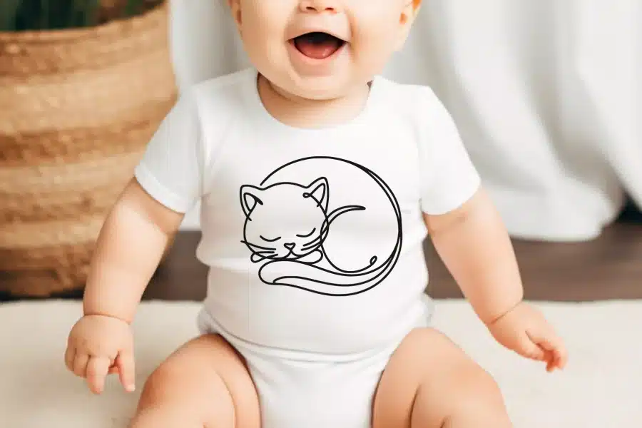 Baby wearing a white onesie with a line drawing of a sleeping cat.