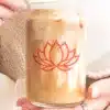 A Person Holds A Glass Iced Coffee Can With A Red Lotus Flower Logo.