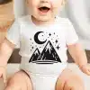 Baby Wearing A White Bodysuit With A Black Mountain Range And Crescent Moon Design.