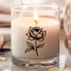 A Lit Candle In A Glass Jar Decorated With A Black And White Floral Design.
