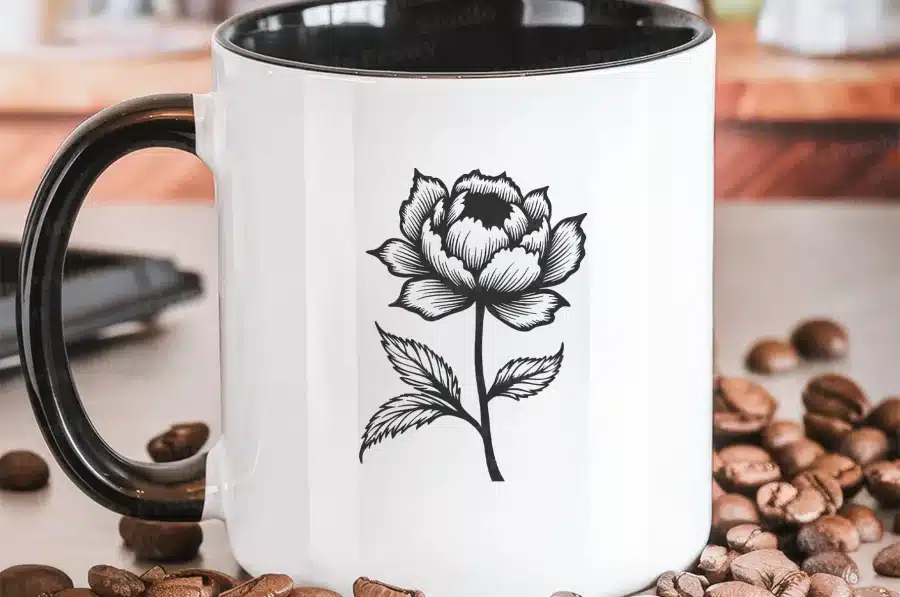 White Coffee Mug With Black Handle And A Black Line Drawing Of A Flower.