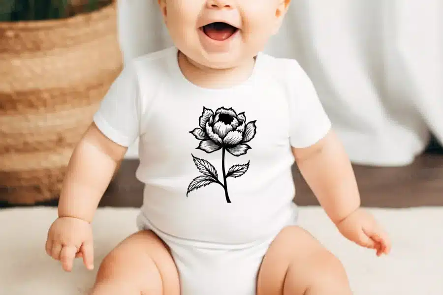 Baby Wearing A White Onesie With A Black Floral Design.