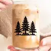 Hands Holding A Glass Of Iced Coffee With A Design Of Three Pine Trees.