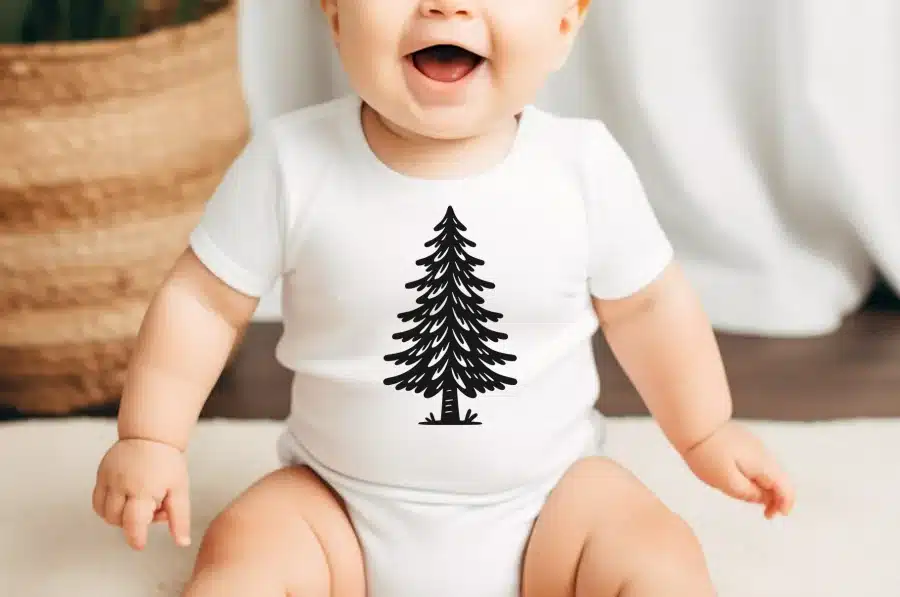 Baby Wearing A White Onesie With A Black Evergreen Tree Design.