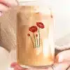 Hands Holding A Glass Iced Coffee With A Poppy Flower Design.