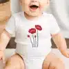 Baby Wearing A White Onesie With A Red Poppy Flower Design.