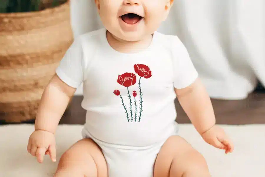 Baby Wearing A White Onesie With A Red Poppy Flower Design.