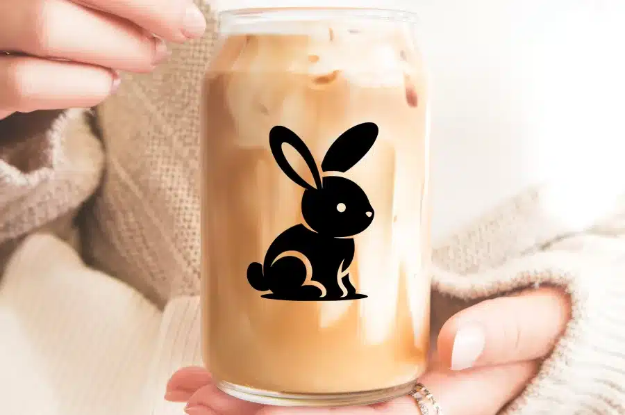 A Glass Of Iced Coffee With A Black Bunny Silhouette Design.