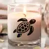 A Lit Candle With A Sea Turtle Graphic.