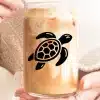 Close-Up Of Hands Holding A Glass Iced Coffee With A Sea Turtle Decal.