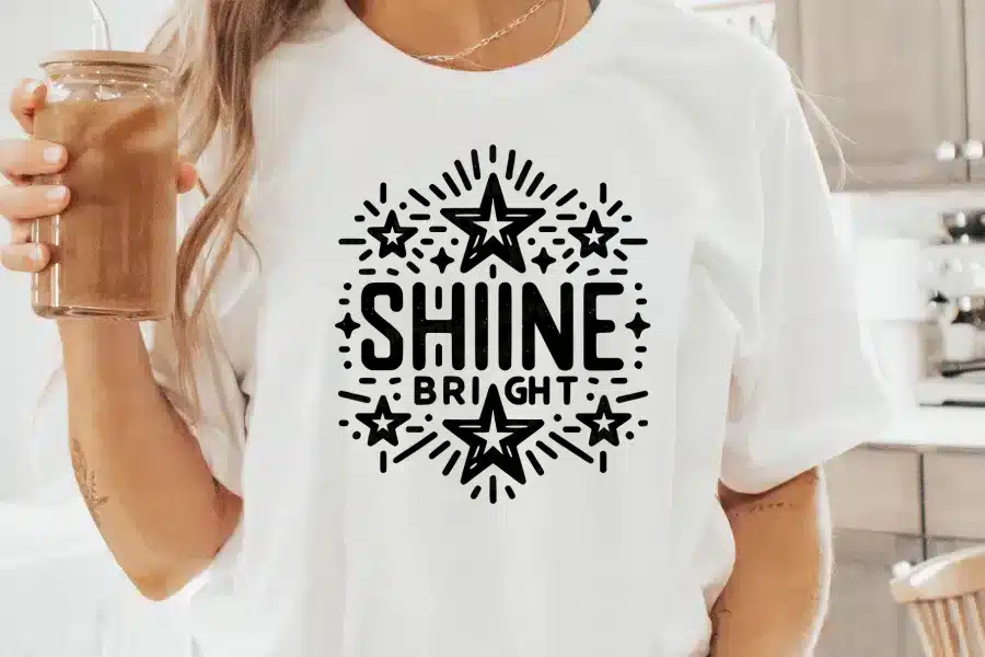 Woman wearing a white t-shirt with a Shine Bright design featuring stars.