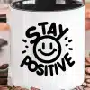 White Coffee Mug With A Black Handle, Featuring A Black Graphic That Says Stay Positive And Includes A Smiling Face.